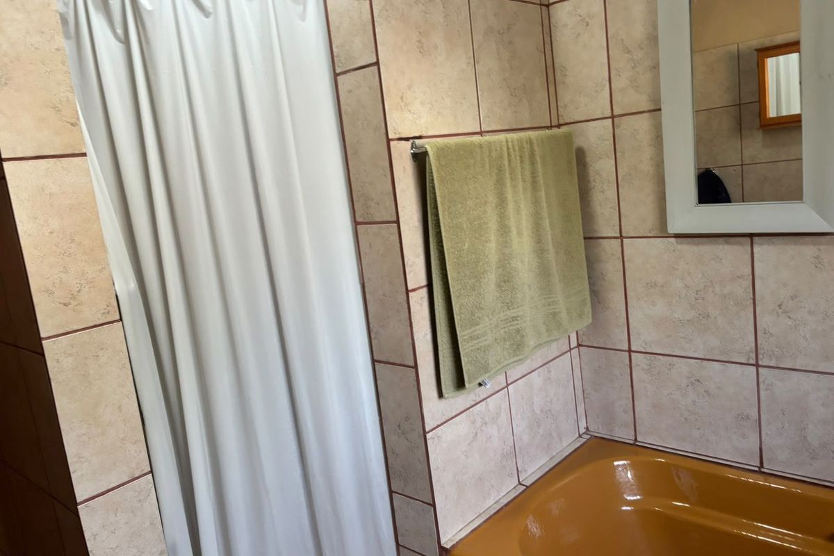 A functional bathroom featuring tiled walls, a built-in bathtub, and a wall-mounted mirror.