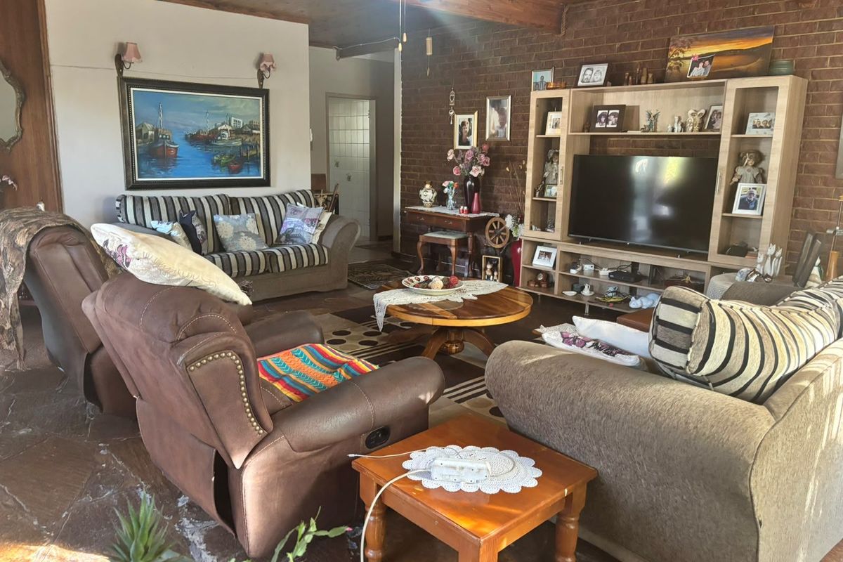 Spacious living room featuring rustic exposed brick walls, a warm timber ceiling, and natural stone flooring, creating a cozy and traditional atmosphere.