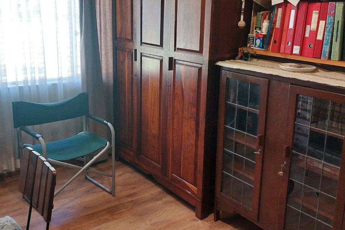 A bedroom featuring built-in wooden cabinetry and laminate flooring, providing functional storage space.