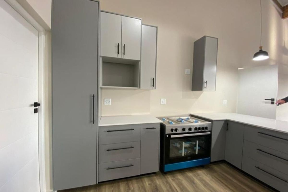 Modern kitchen featuring grey cabinetry, white countertops, and a stainless steel freestanding oven with gas hob.