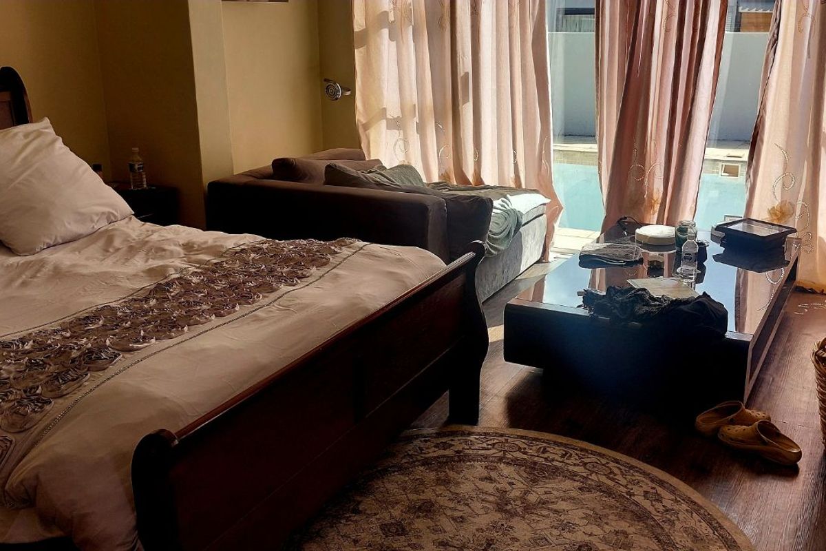A bedroom featuring laminate flooring and large sliding glass doors that provide direct access to an outdoor pool area.