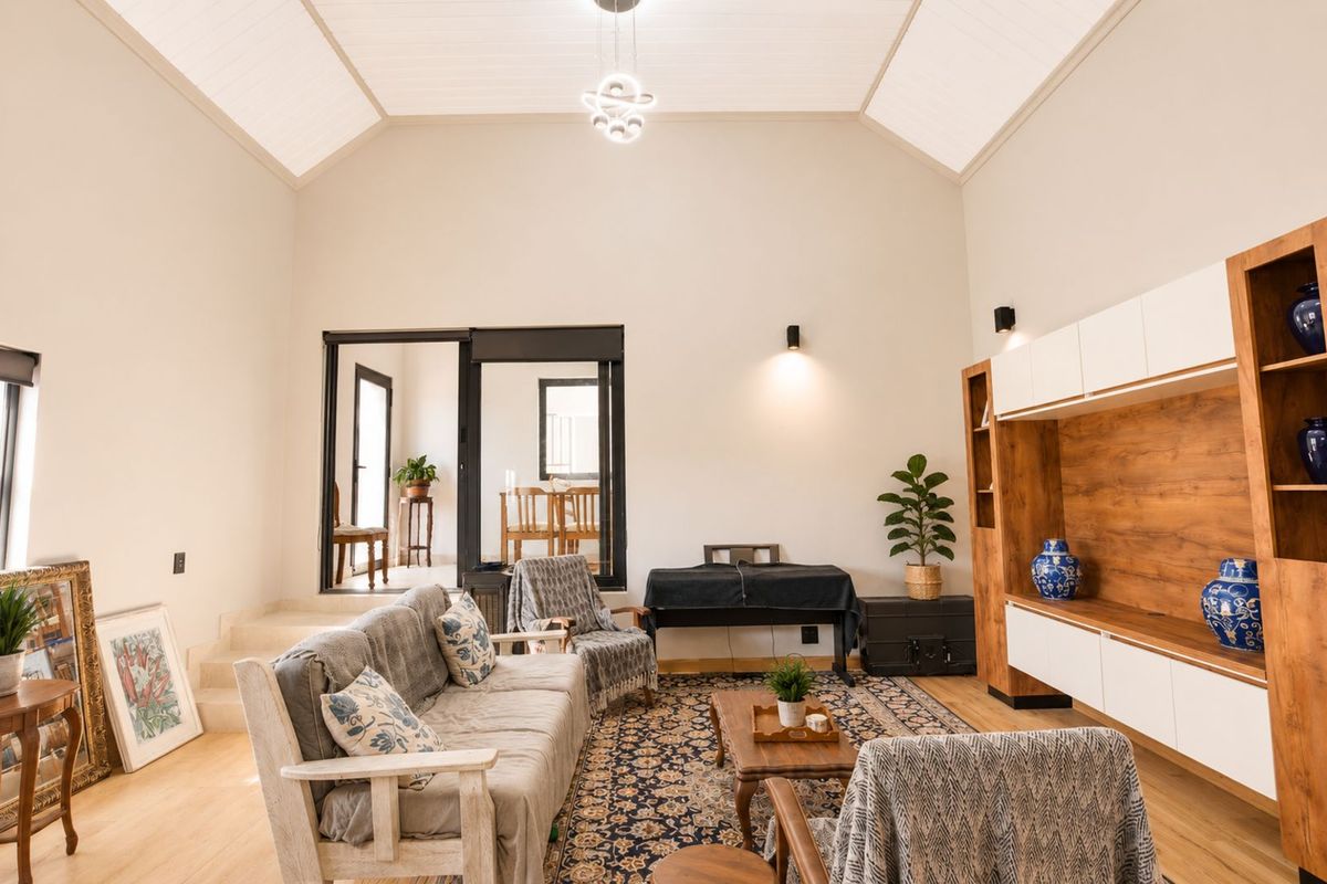 Spacious living room featuring high vaulted ceilings, wood-look flooring, and a large built-in media unit with integrated cabinetry.