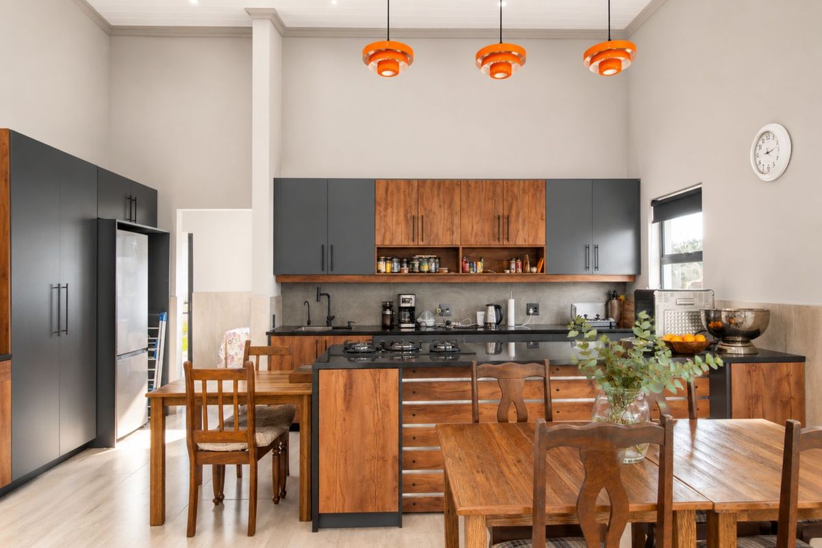 Modern kitchen featuring two-tone cabinetry, dark stone countertops, integrated gas cooktop, and high ceilings with contemporary pendant lighting.
