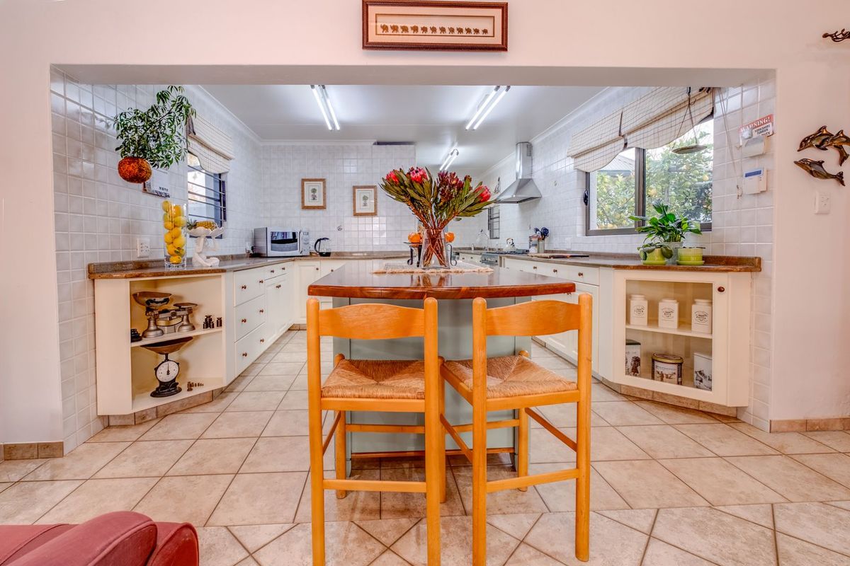 A functional kitchen featuring a central island with a wooden countertop, tiled splashbacks, and built-in cabinetry with integrated storage.