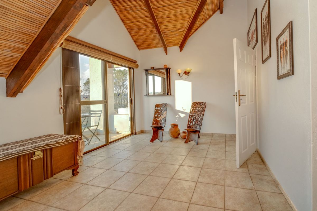 A bright bedroom featuring a vaulted bamboo ceiling, tiled flooring, and sliding glass doors leading to an outdoor balcony area.