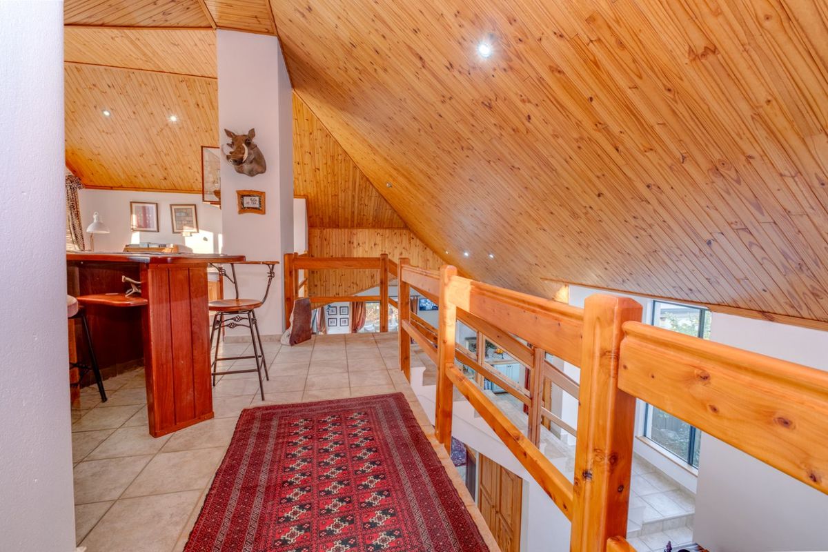 A mezzanine level overlooking the lower floor, featuring vaulted timber-clad ceilings, tiled flooring, and a wooden balustrade.