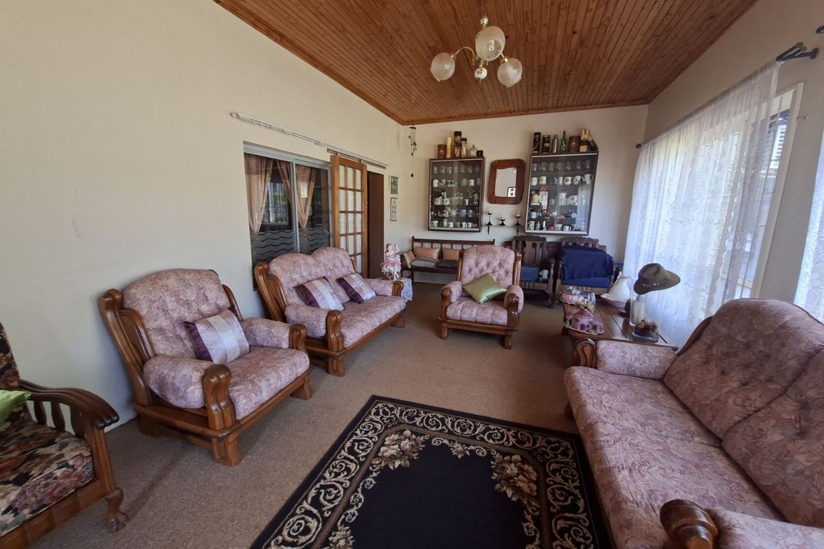 A traditional living room featuring a timber-clad ceiling, carpeted flooring, and built-in display cabinetry, offering a classic and comfortable living space.