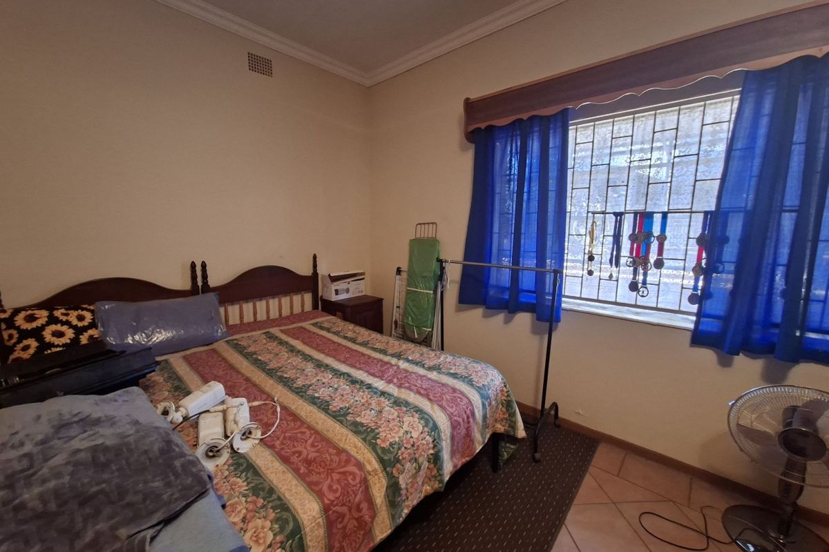 A bedroom featuring tiled flooring, a window with security bars, and crown molding.