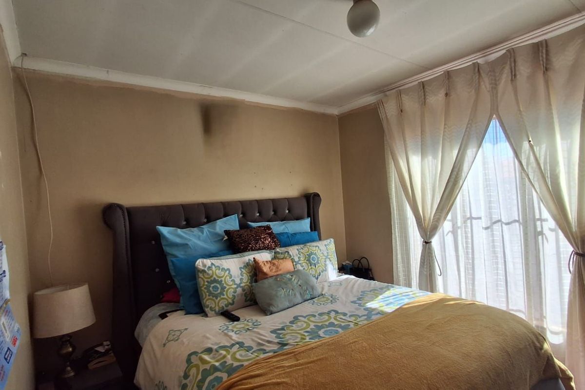 A bedroom featuring a window with curtains and a central ceiling light fixture.
