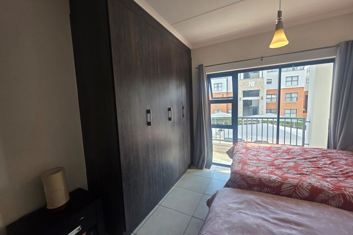 A bedroom featuring built-in dark wood cabinetry and large sliding glass doors that open onto a private balcony.
