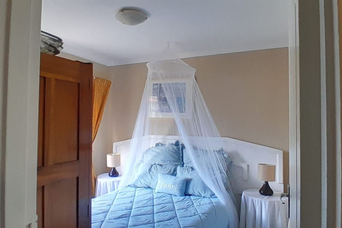 A view into a bedroom featuring a built-in headboard and a flush-mount ceiling light fixture.