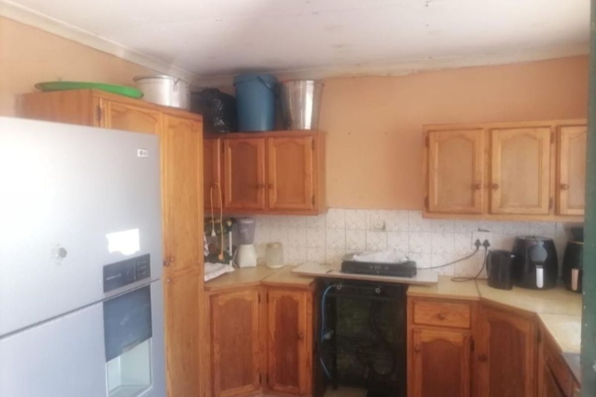A dated kitchen featuring wooden cabinetry, tiled splashbacks, and a functional layout, offering potential for modernization and renovation.
