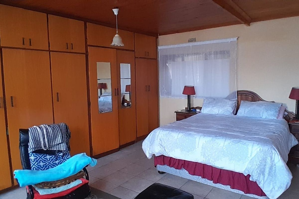 A spacious bedroom featuring extensive built-in wooden cabinetry, tiled flooring, and a timber-paneled ceiling.