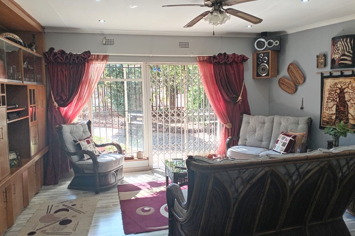 A comfortable living room featuring built-in wooden cabinetry, a ceiling fan, and sliding glass doors with security gates leading to the exterior.