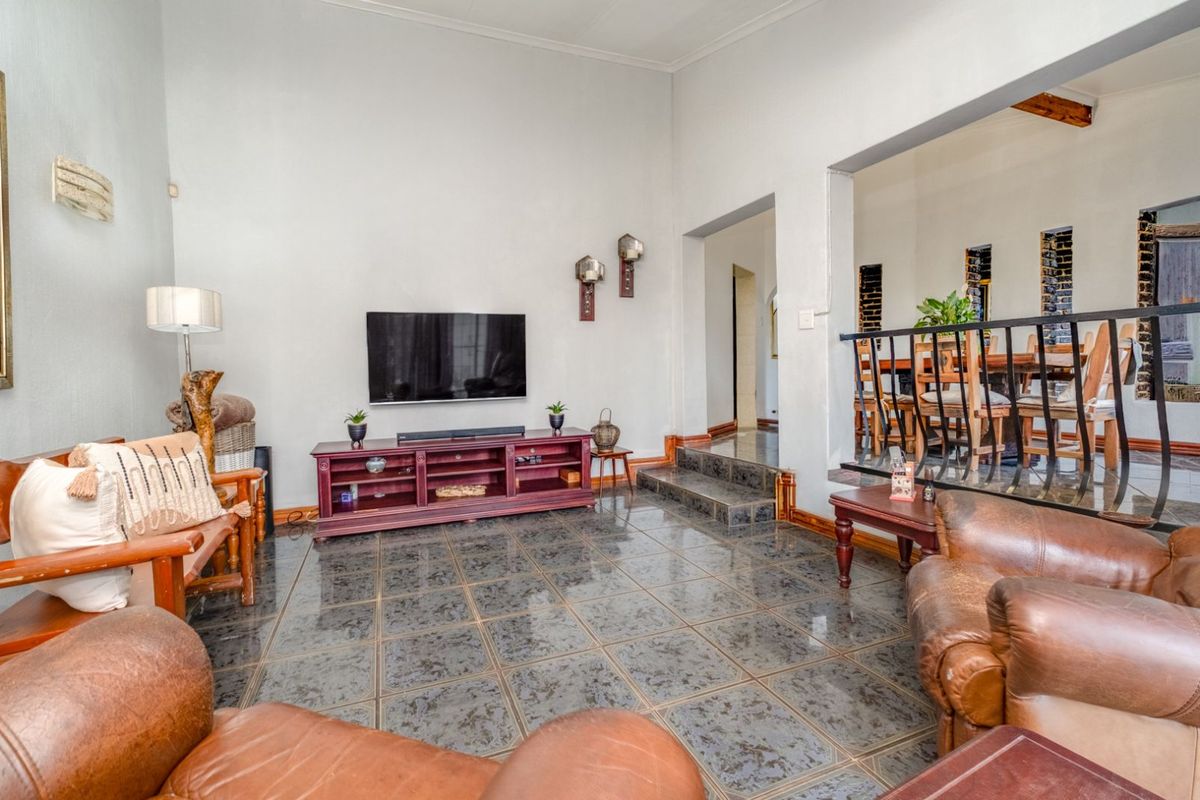 Spacious living area featuring high ceilings, dark tiled flooring, and an open-plan layout connecting to the adjacent dining space.