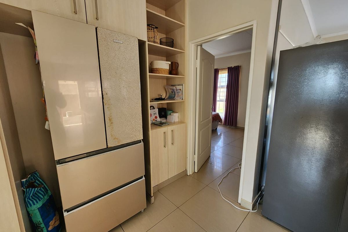 A functional kitchen area featuring built-in cabinetry, shelving, and tiled flooring, with a doorway leading into an adjacent bedroom.