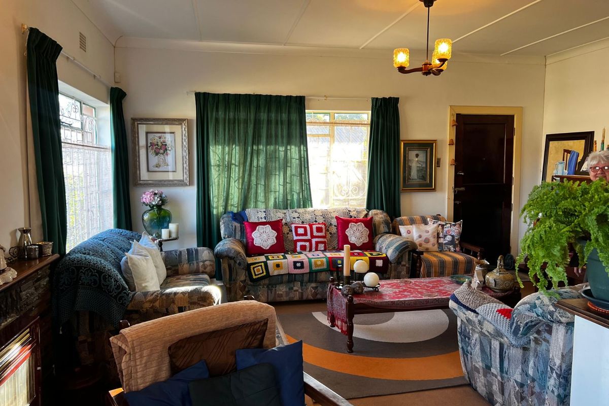 A cozy living room featuring large windows, traditional ceiling light fixtures, and a classic layout with ample natural light.