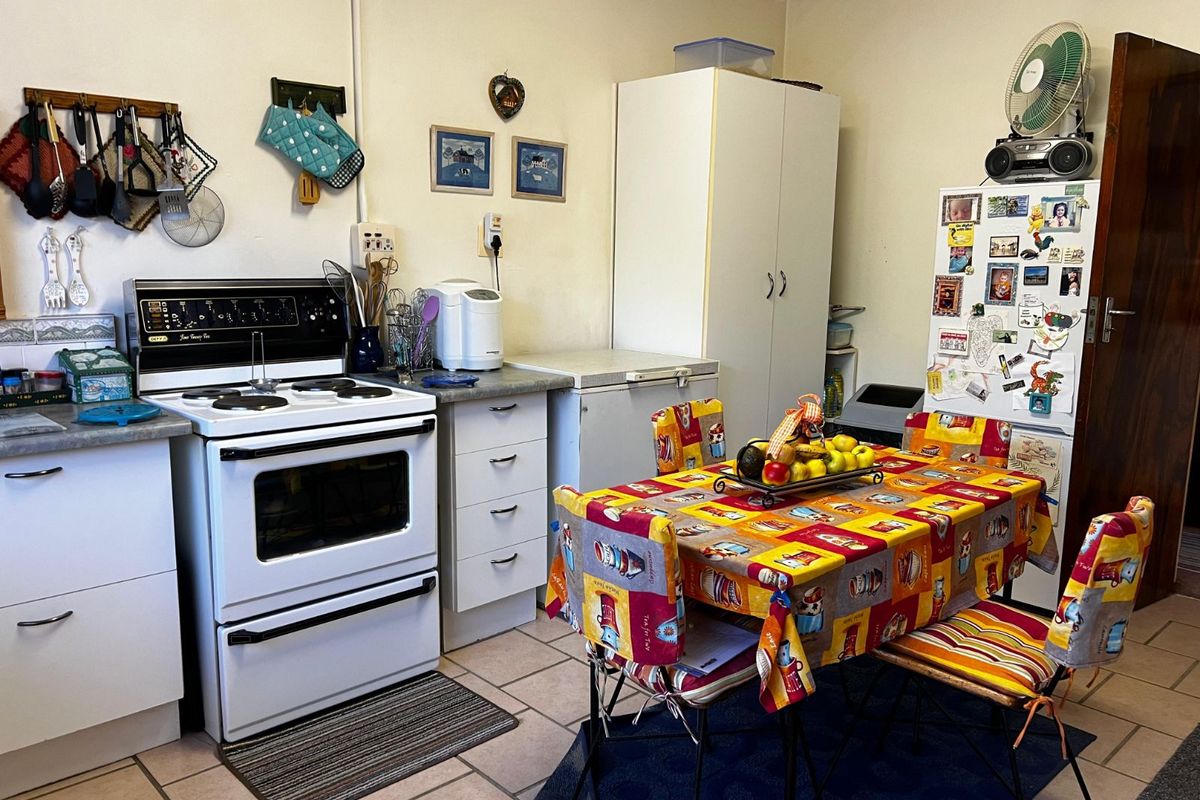 A functional kitchen featuring a freestanding stove, tiled flooring, and built-in cabinetry, offering a practical layout for daily meal preparation.