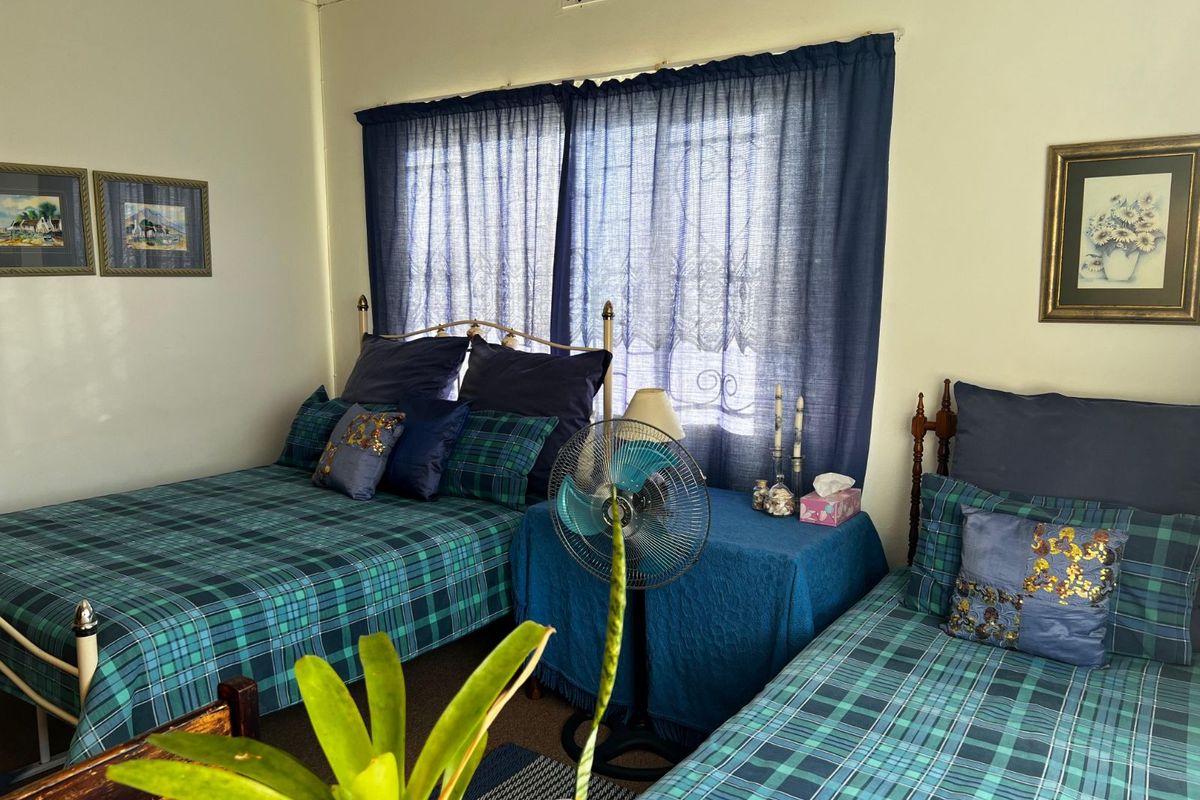 A bedroom featuring a window with security bars and a ceiling ventilation vent.