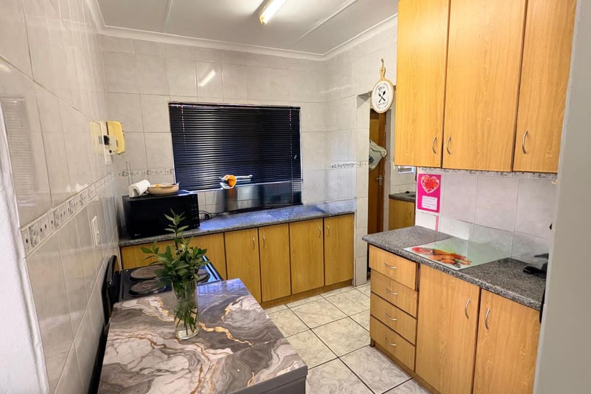 Functional kitchen featuring light wood-finish cabinetry, granite-look countertops, full wall tiling, and tiled flooring.