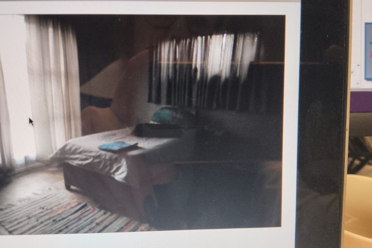 A bedroom featuring large windows with curtains, providing natural light access to the space.