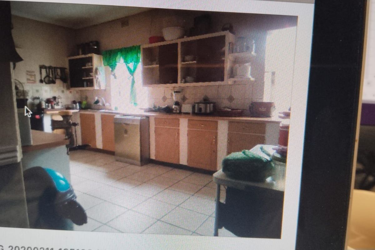 A dated kitchen featuring original cabinetry, tiled flooring, and a functional layout, offering significant potential for a modern renovation.