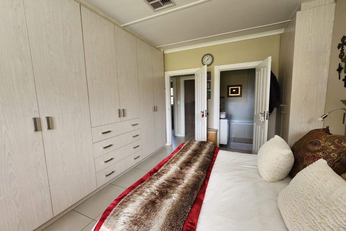 Spacious bedroom featuring extensive built-in cupboards, tiled flooring, and direct access to an en-suite bathroom.