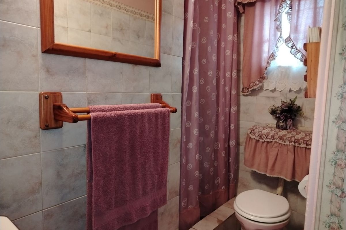 A functional bathroom featuring tiled walls, a built-in shower area with a curtain, a wall-mounted mirror, and a standard toilet.