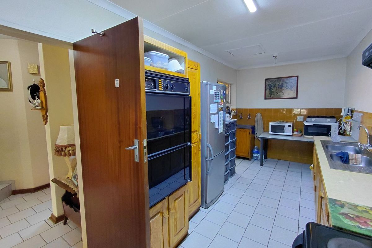 A functional kitchen featuring built-in double ovens, tiled splashbacks, and a double stainless steel sink with ample counter space.
