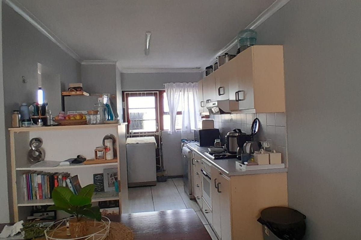 A functional kitchen area featuring built-in cabinetry, a gas hob, and an integrated oven, with an adjacent laundry space visible.