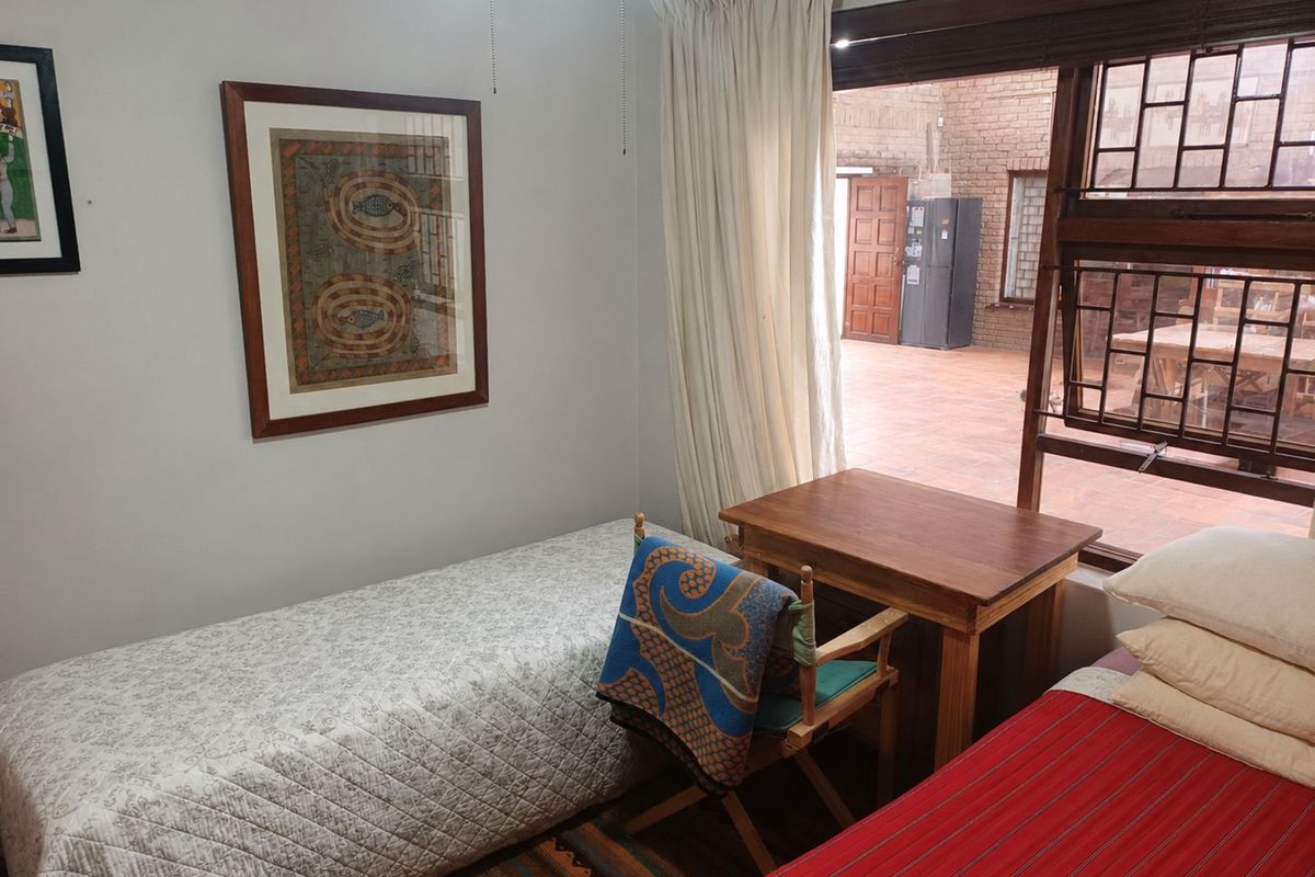 A bedroom featuring a large window with security bars, providing natural light and access to an outdoor patio area.