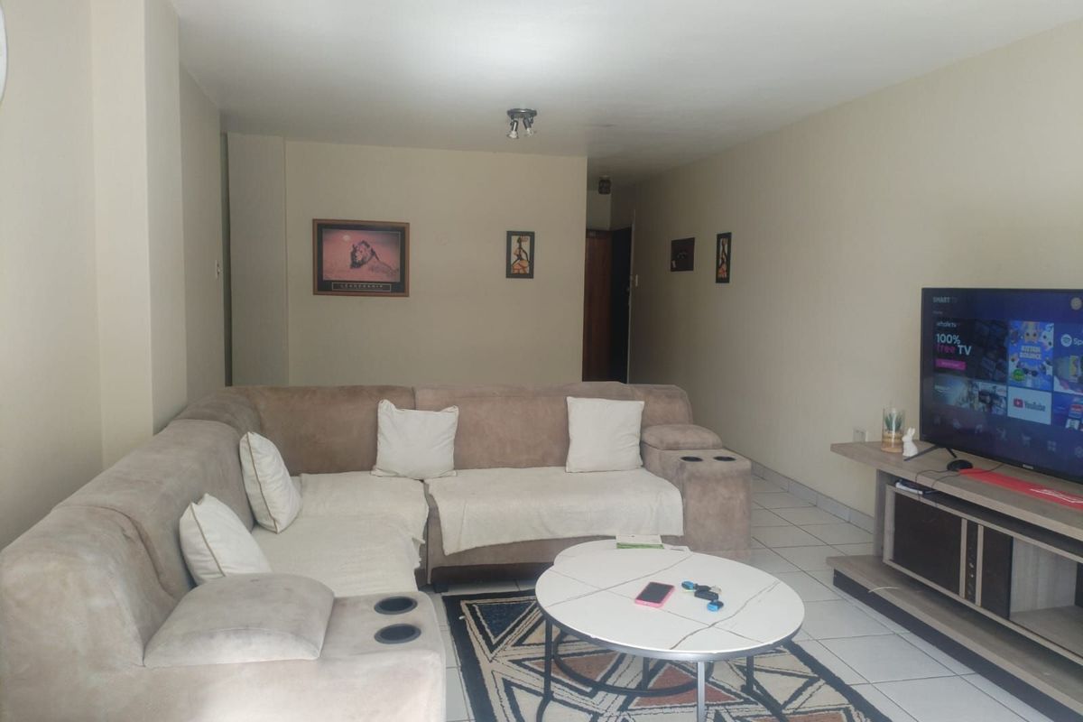 A comfortable living room featuring tiled flooring and neutral wall tones, providing a functional and inviting space for relaxation.