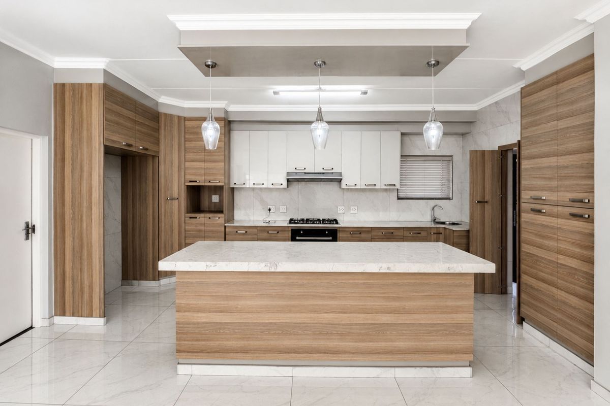 Modern kitchen featuring a central island with stone countertop, integrated cabinetry, built-in gas hob, extractor fan, and polished tile flooring.