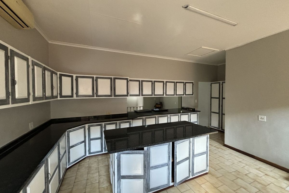 Spacious kitchen featuring extensive cabinetry, dark granite countertops, a central island, and tiled flooring, offering ample storage and workspace.