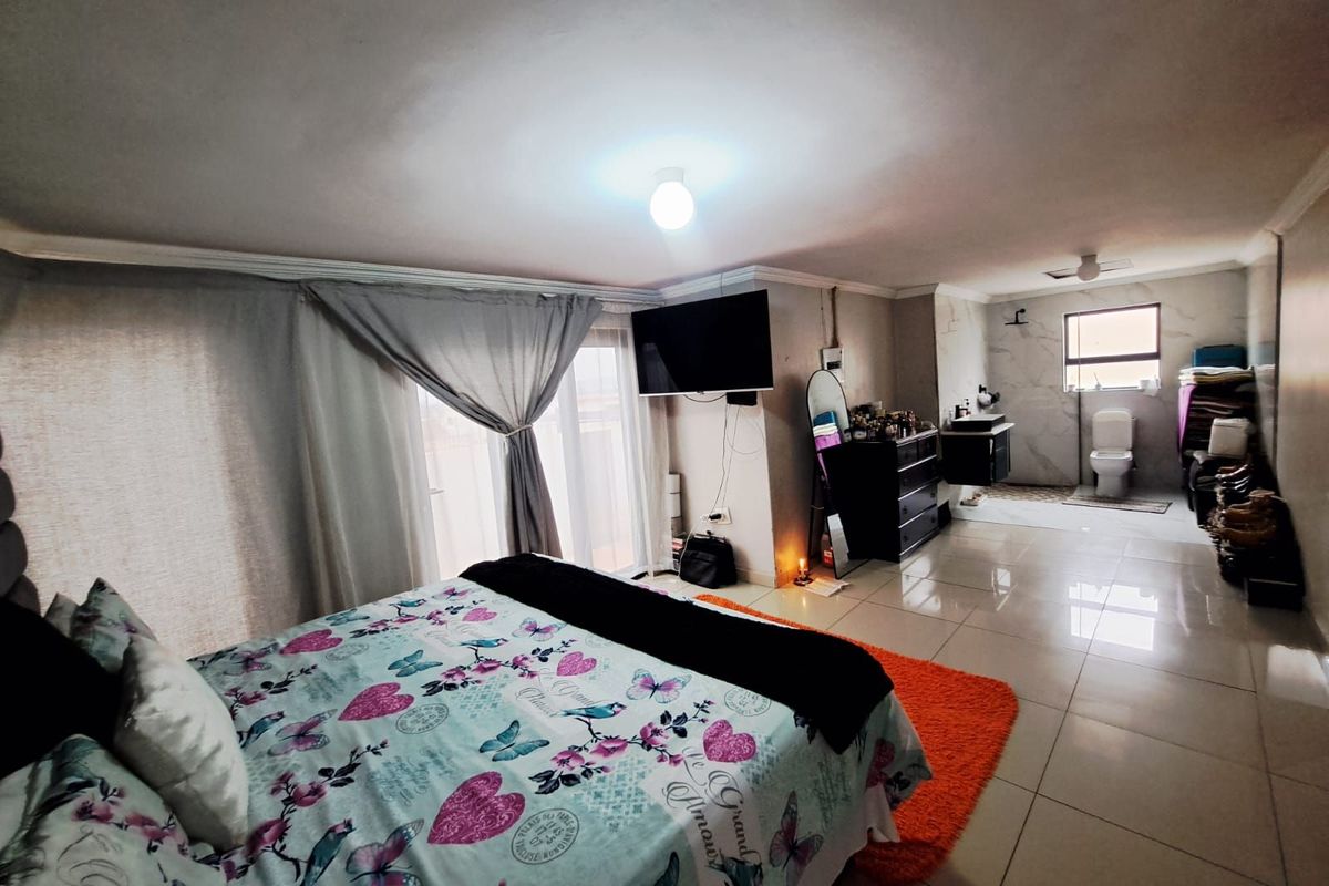 Spacious open-plan bedroom featuring large format floor tiles, sliding glass doors, and an integrated en-suite bathroom area with modern fixtures.