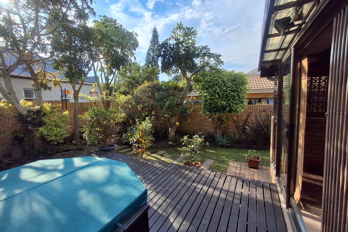 A private rear garden featuring a timber deck, established landscaping, and a brick boundary wall, providing a peaceful outdoor retreat.