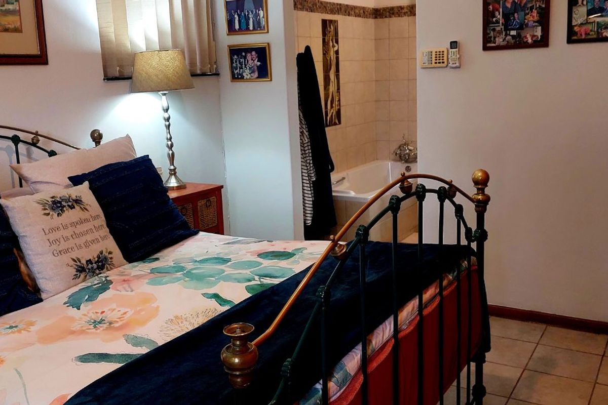 A bedroom featuring tiled flooring and an open-plan en-suite bathroom area with a built-in bathtub.