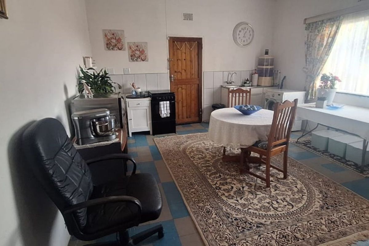 A multi-purpose kitchen and dining area featuring tiled flooring, a built-in sink unit, and a freestanding stove.