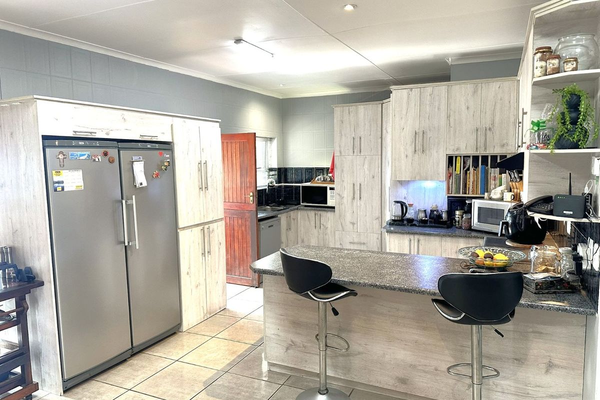A functional kitchen featuring light wood-grain cabinetry, granite countertops, a breakfast bar, and tiled flooring, offering ample storage and workspace.