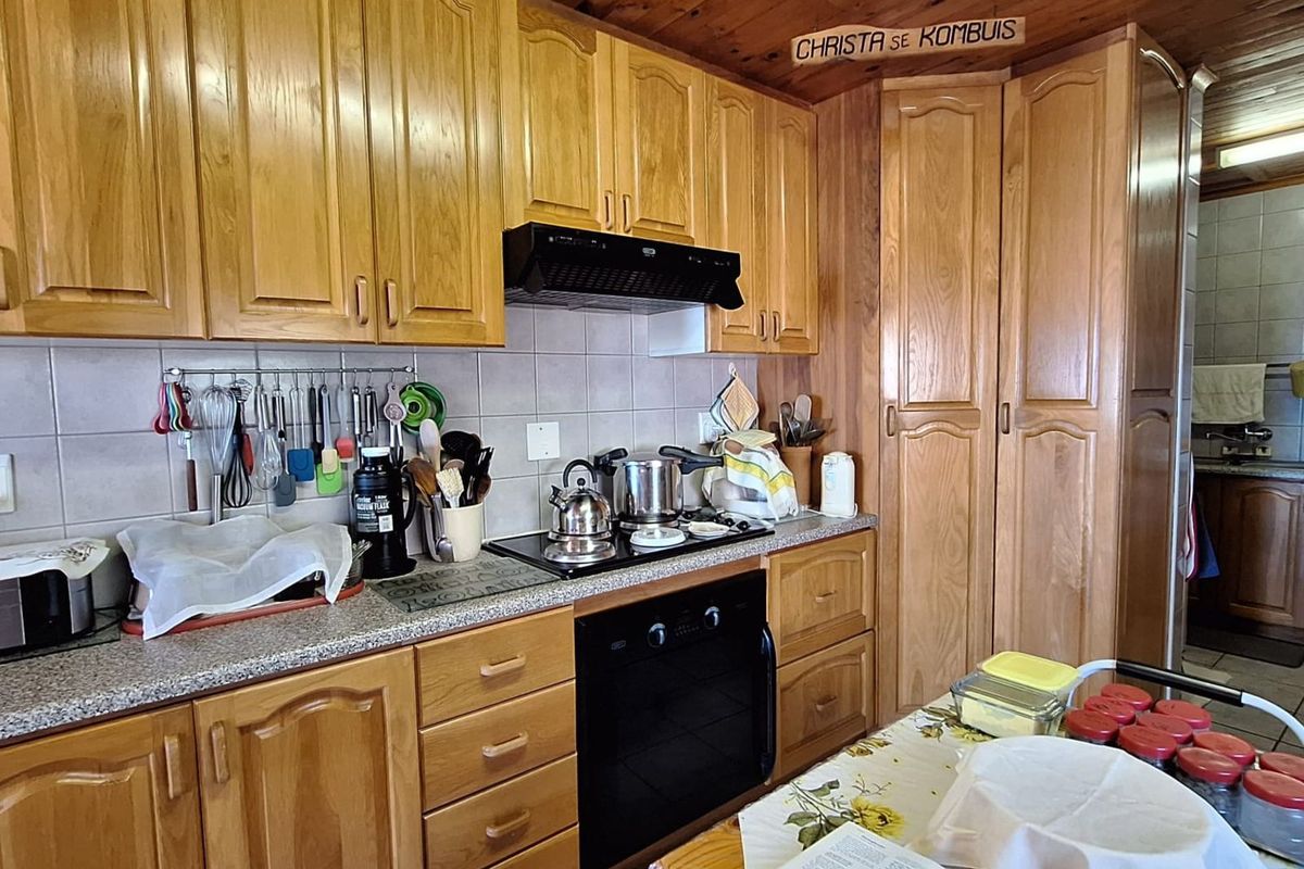 A traditional kitchen featuring timber cabinetry, a built-in oven, extractor fan, and tiled splashbacks with a rustic wood-paneled ceiling.
