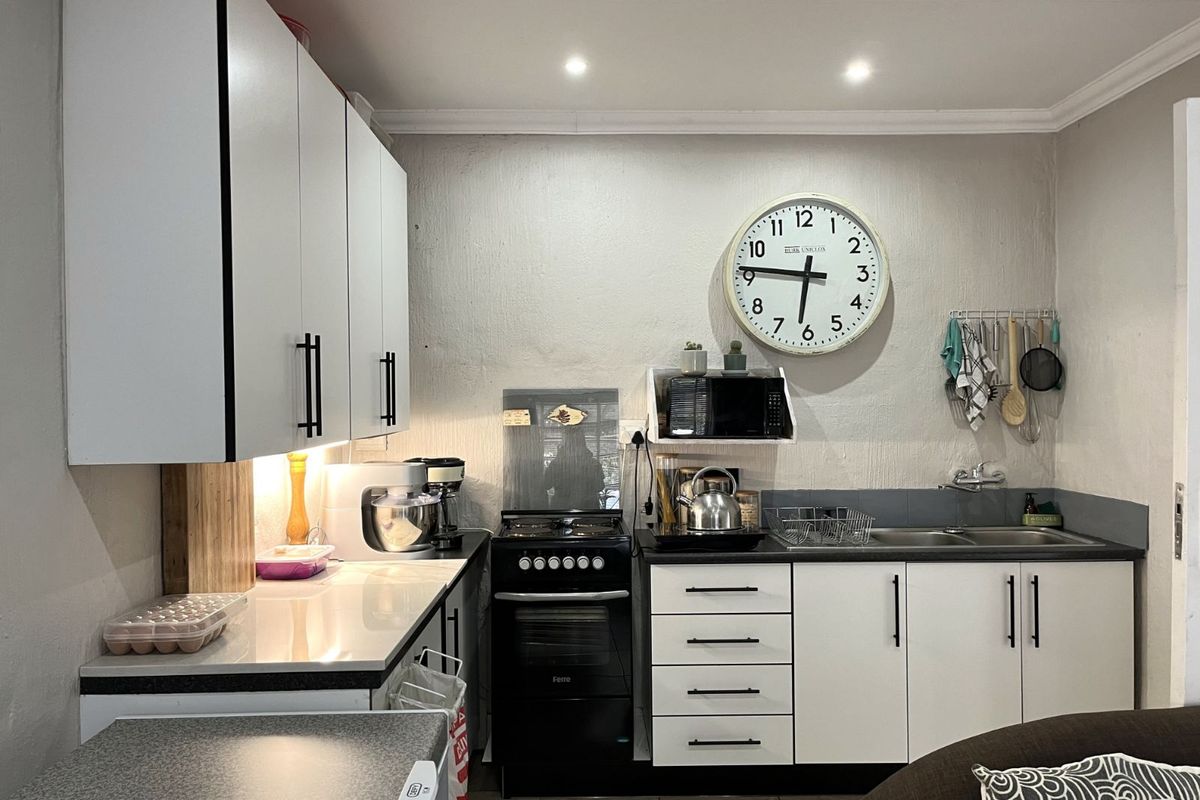 Compact kitchen featuring white cabinetry, dark countertops, a built-in stove, and a double sink, offering a functional and efficient workspace.