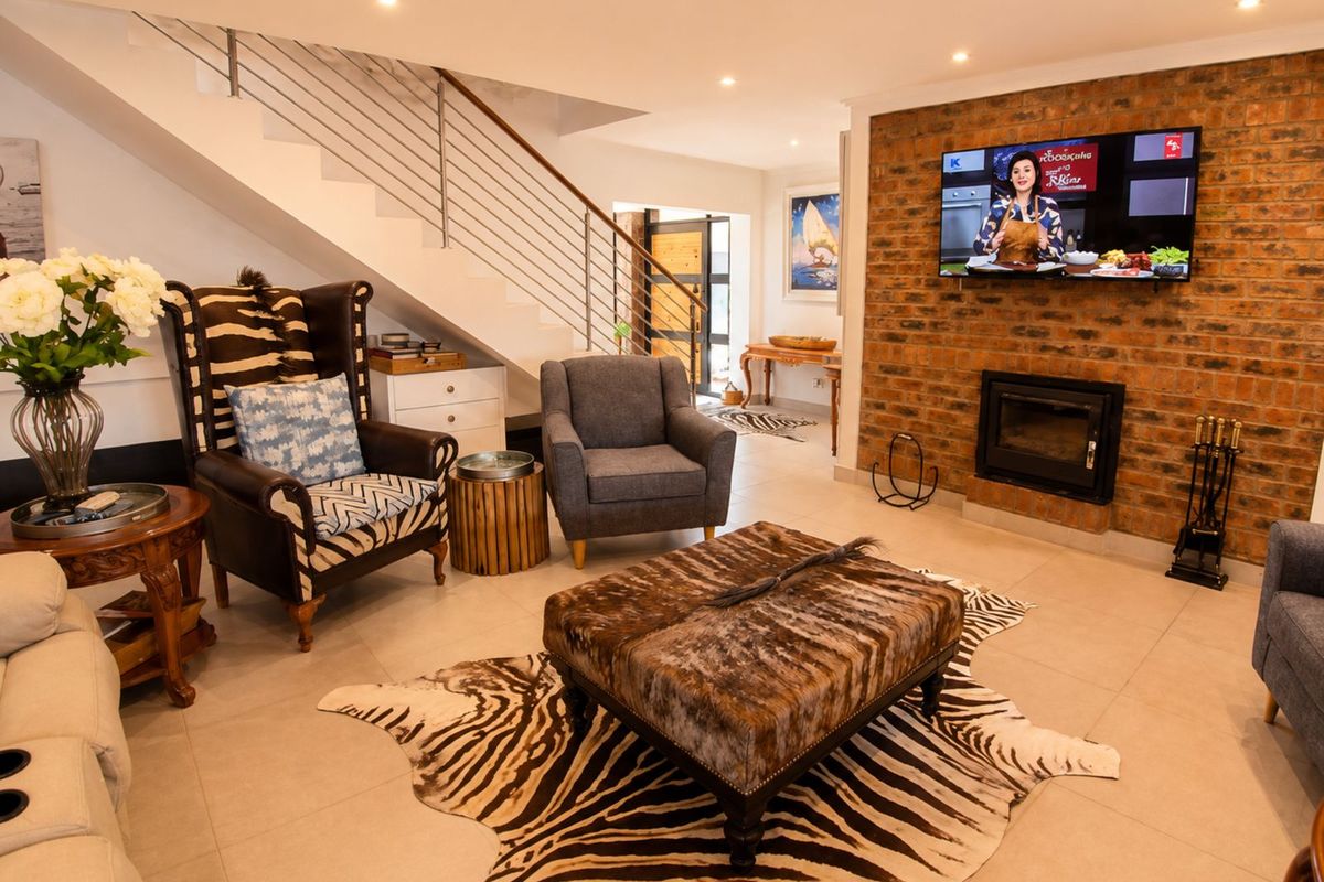 Spacious living area featuring a prominent exposed brick feature wall with a built-in fireplace and staircase with modern stainless steel balustrades.