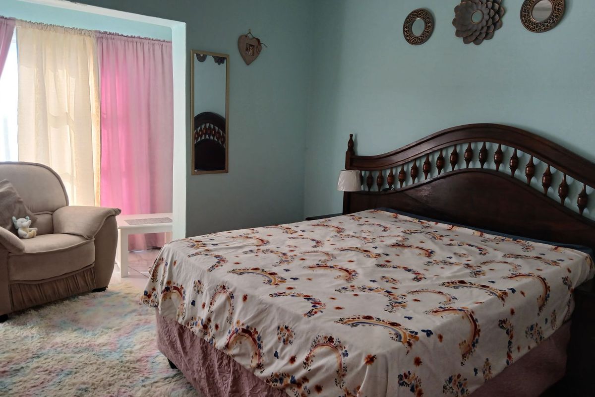 A spacious bedroom featuring a large bed and an adjoining seating area with natural light through the window.