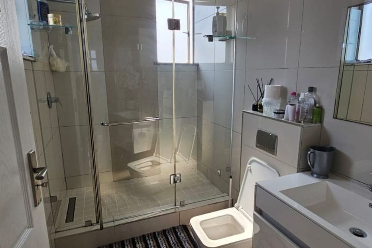Modern bathroom featuring a glass-enclosed walk-in shower, wall-mounted toilet with concealed cistern, and a sleek vanity basin with integrated storage.