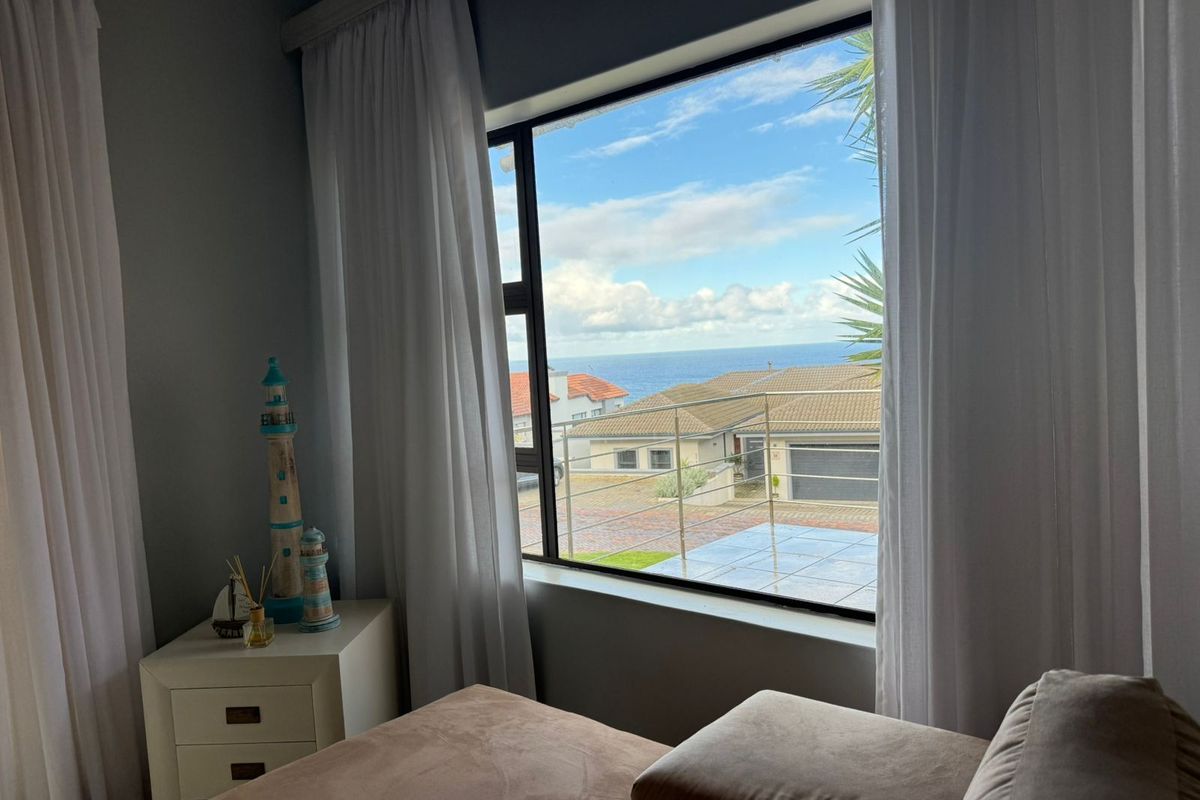 A bedroom featuring a large window with views of the surrounding neighborhood and the ocean.