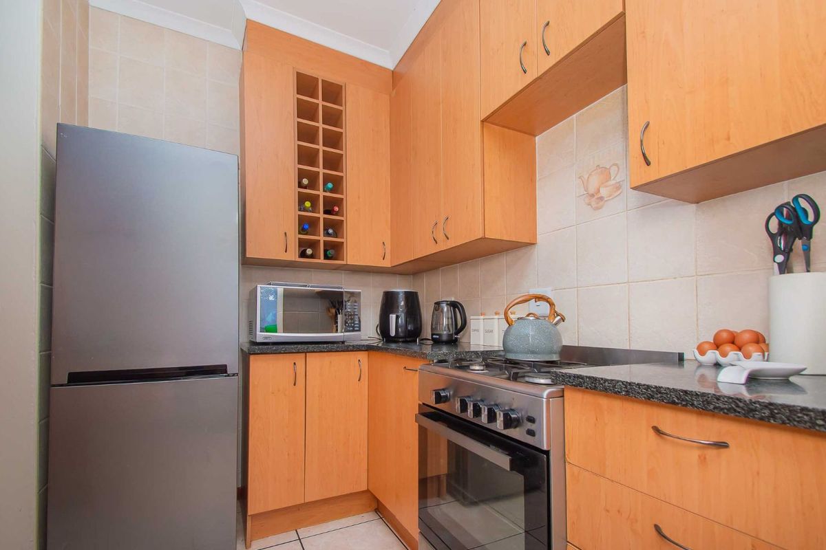 A compact kitchen featuring light wood-finish cabinetry, granite countertops, tiled backsplash, and a built-in gas stove with oven.