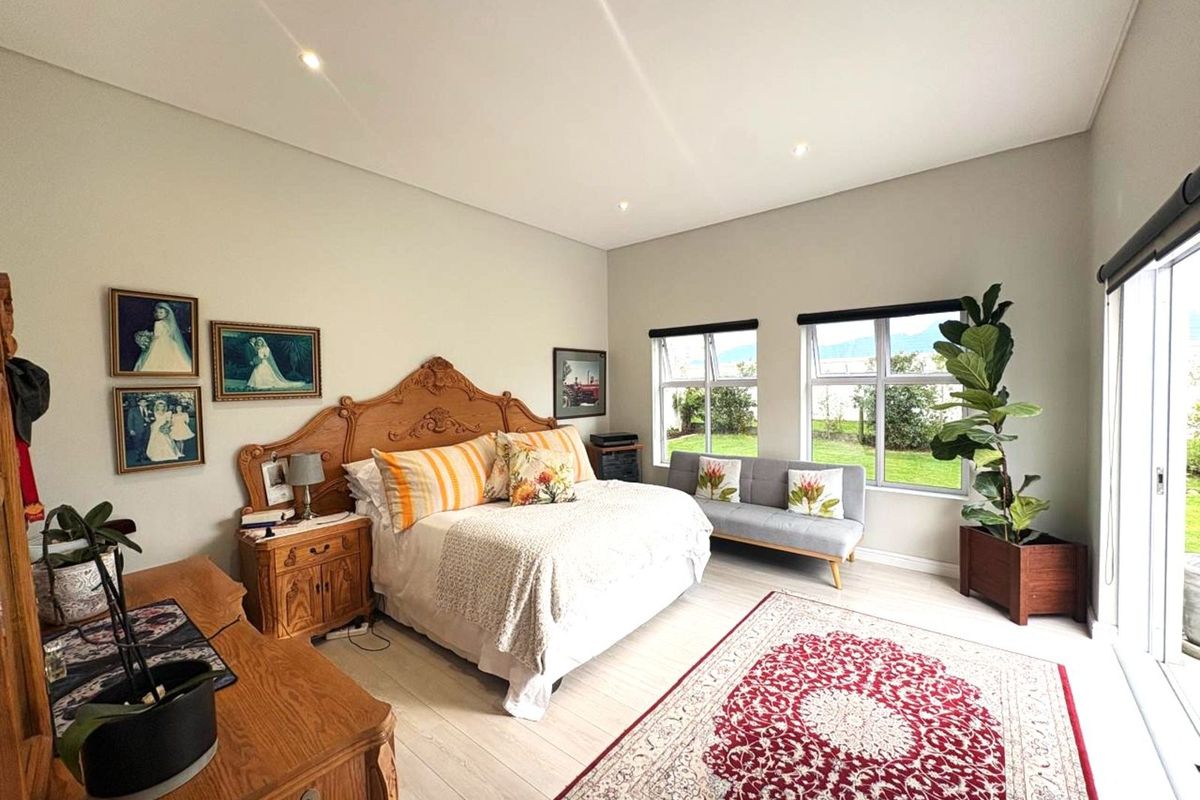 Spacious bedroom featuring light-toned flooring, recessed ceiling lighting, and large windows providing natural light and garden views.