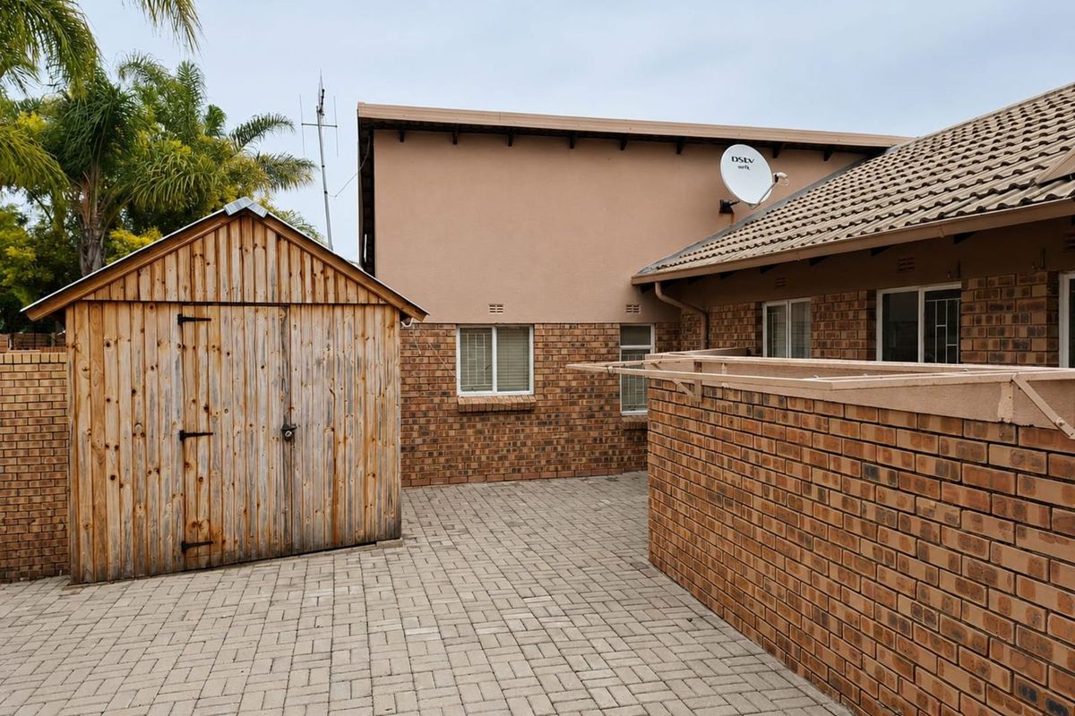 A rear courtyard area featuring paved flooring, a wooden storage shed, and brick boundary walls, providing a functional outdoor utility space.