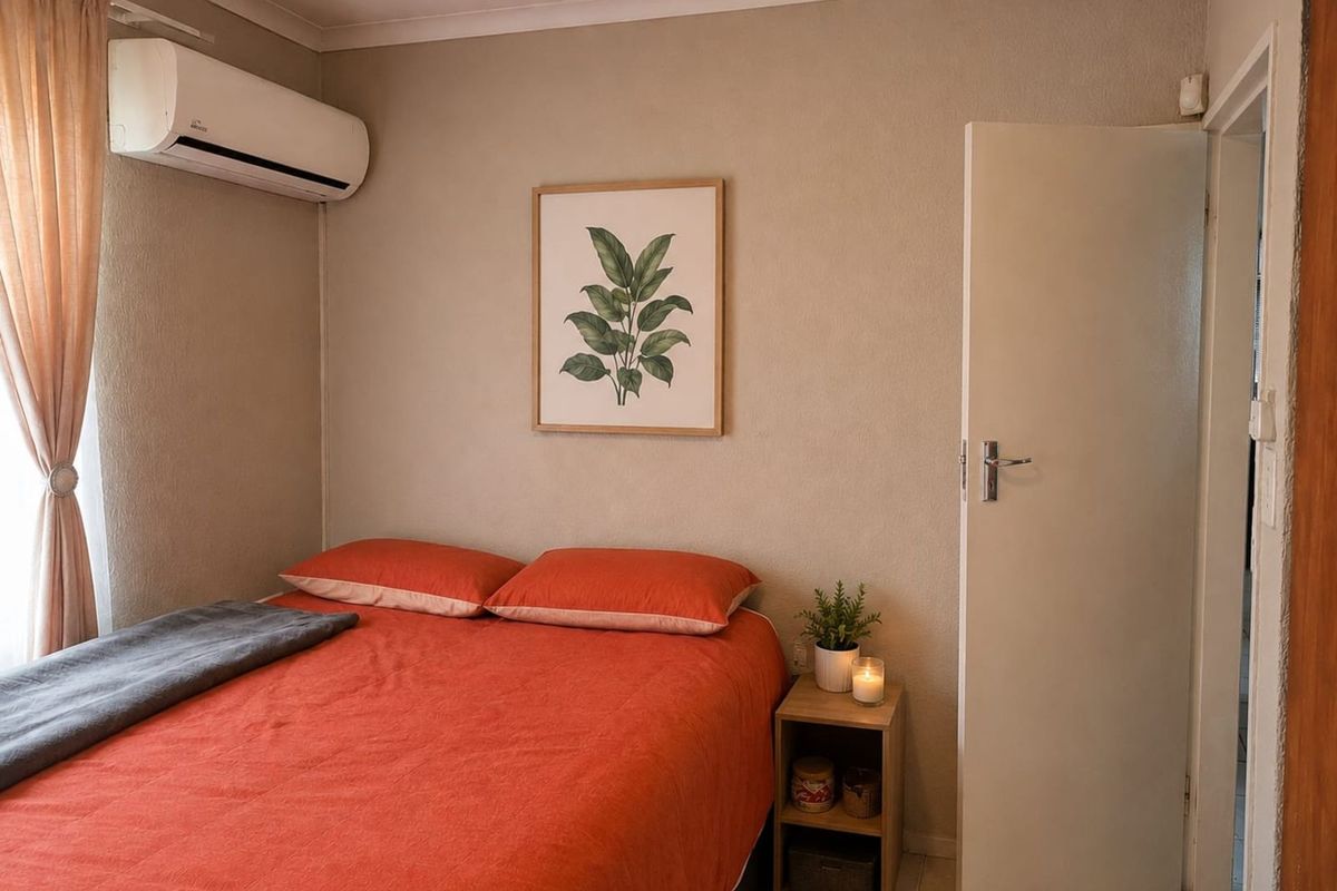 A cozy bedroom featuring a wall-mounted air conditioning unit, neutral wall finishes, and tiled flooring.