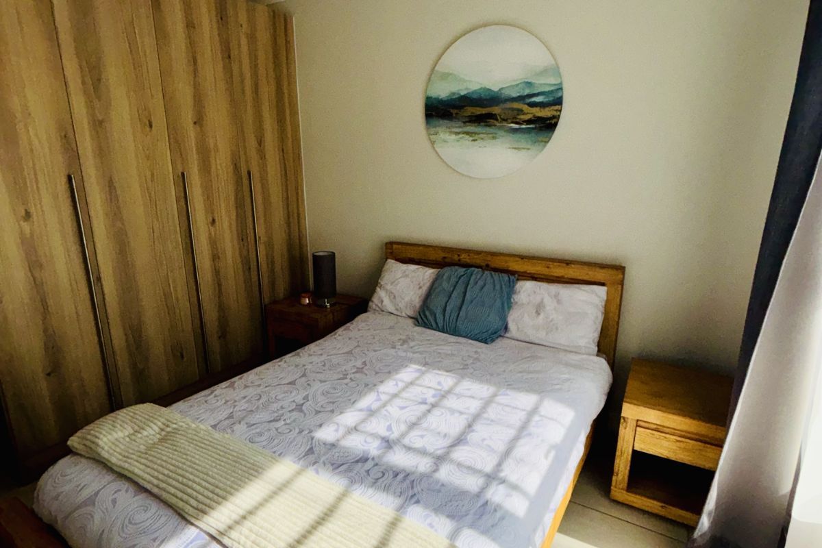 A cozy bedroom featuring built-in wooden wardrobes, tiled flooring, and a pendant light fixture, creating a warm and functional living space.